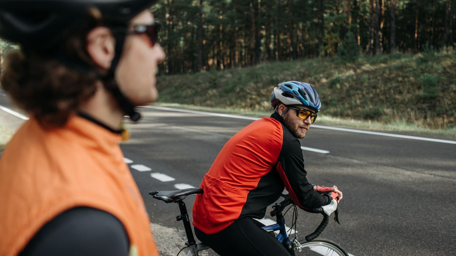 Deux cyclistes roulant sur une route bordée d'arbres