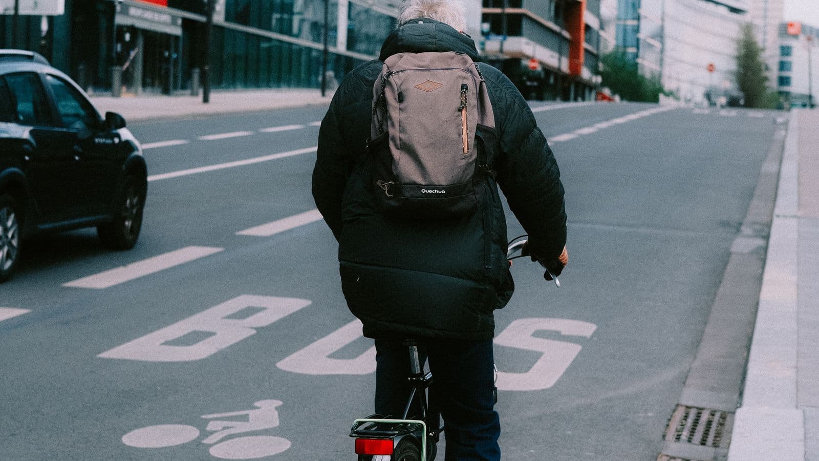 Cycliste avec un sac à dos roulant sur une bande cyclable en ville